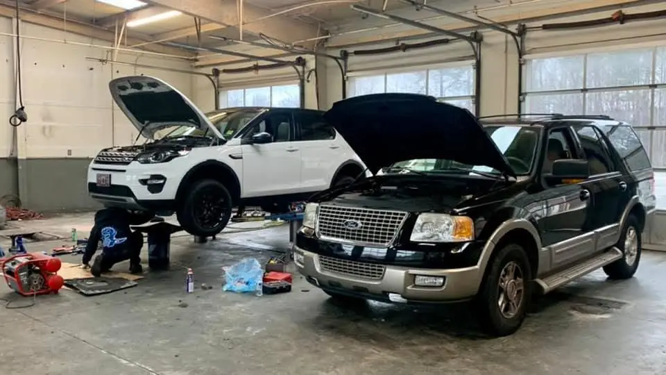 Two vehicles with hoods open in the iShop service bay